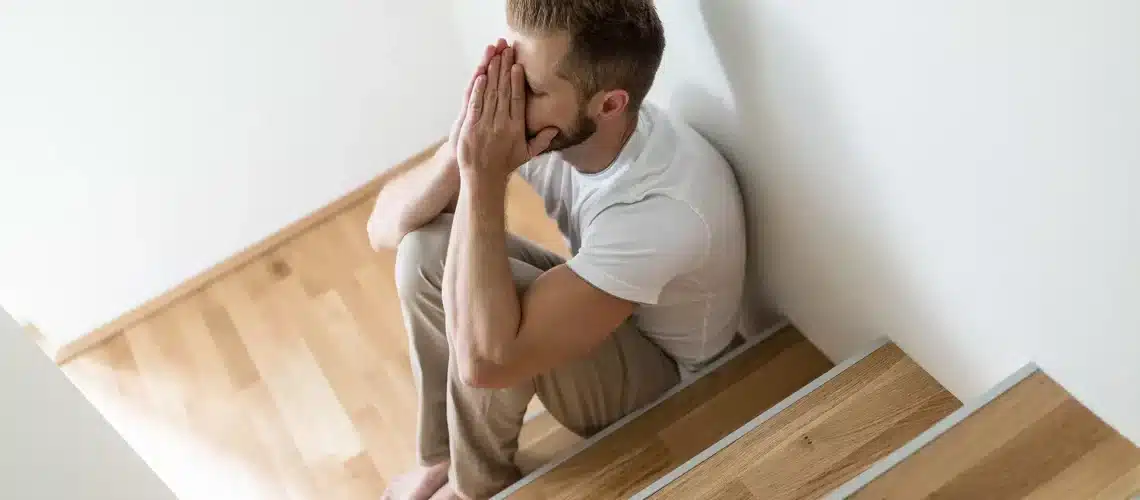 hypnosis, hypnotherapy, health A man sitting on the stairs with his hand on his face.