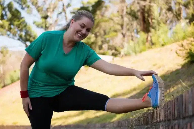 hypnosis, hypnotherapy, health A woman stretching her leg on a brick wall.