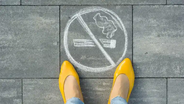 hypnosis, hypnotherapy, health A woman in yellow shoes is standing next to a no smoking sign.