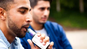 hypnosis, hypnotherapy, health A man is vaping while another man holds a vape pen.