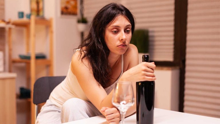 hypnosis, hypnotherapy, health A woman sits quietly at a table, contemplating an unopened wine bottle with an empty glass nearby, reflecting on her alcohol addiction recovery process. 