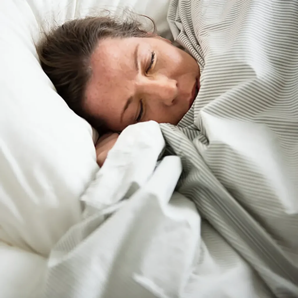 Relaxed woman in bed, using self-hypnosis for improved sleep quality