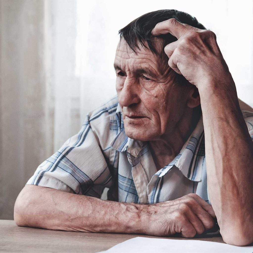 Senior citizen pondering at desk, illustrating self-hypnosis for memory improvement