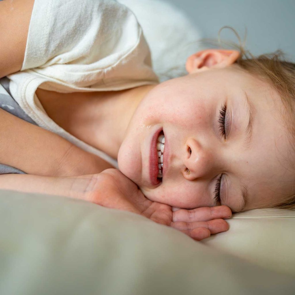 Child enjoying restful sleep post self-hypnosis for teeth grinding.