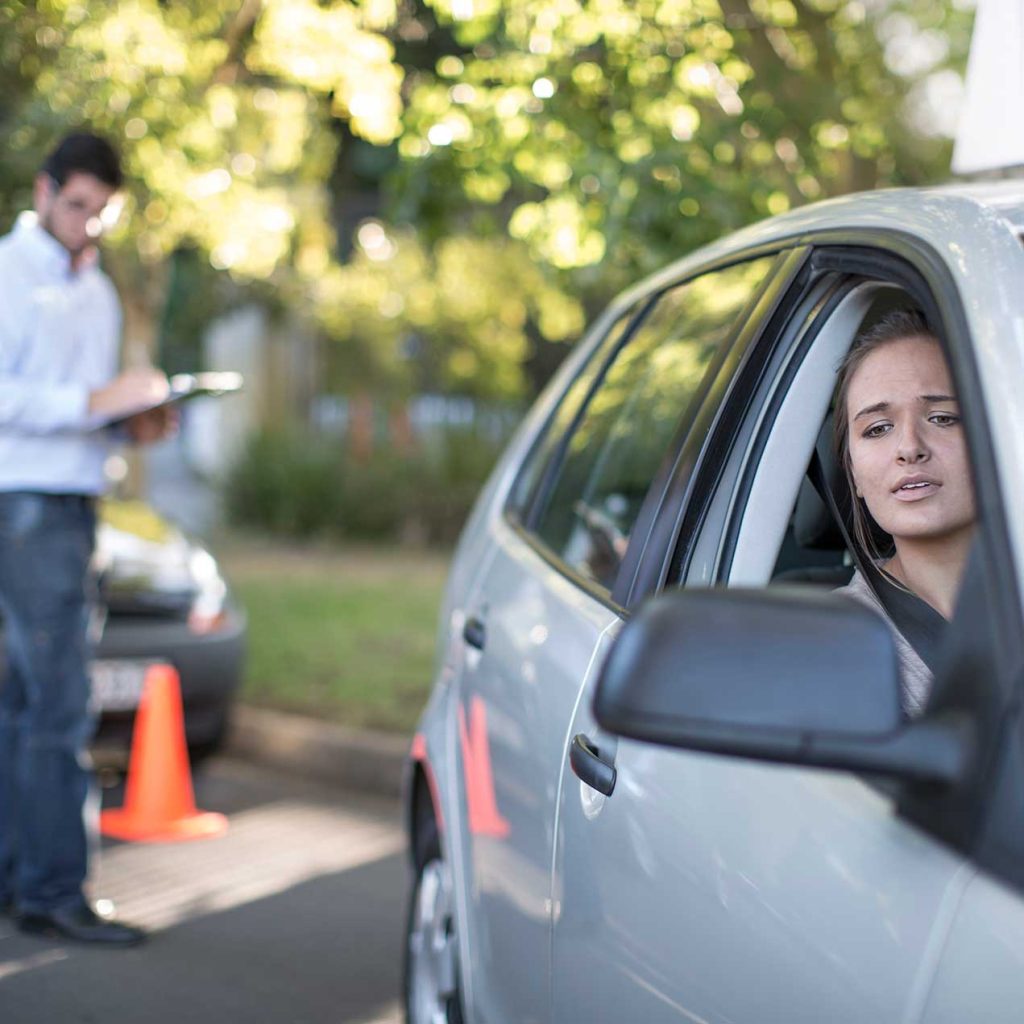 Anxious teenager during driving license test, instructor observing