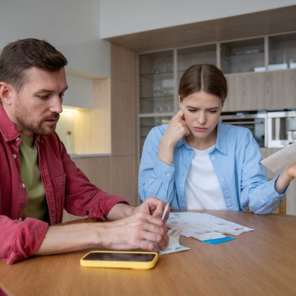 Stressed couple reviewing financial documents, symbolising financial stress