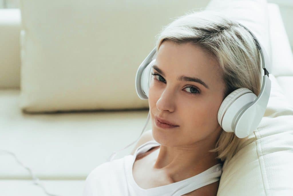 A Woman Wearing Headphones On A Couch, Seemingly Lost In The Realms Of Hypnosis.