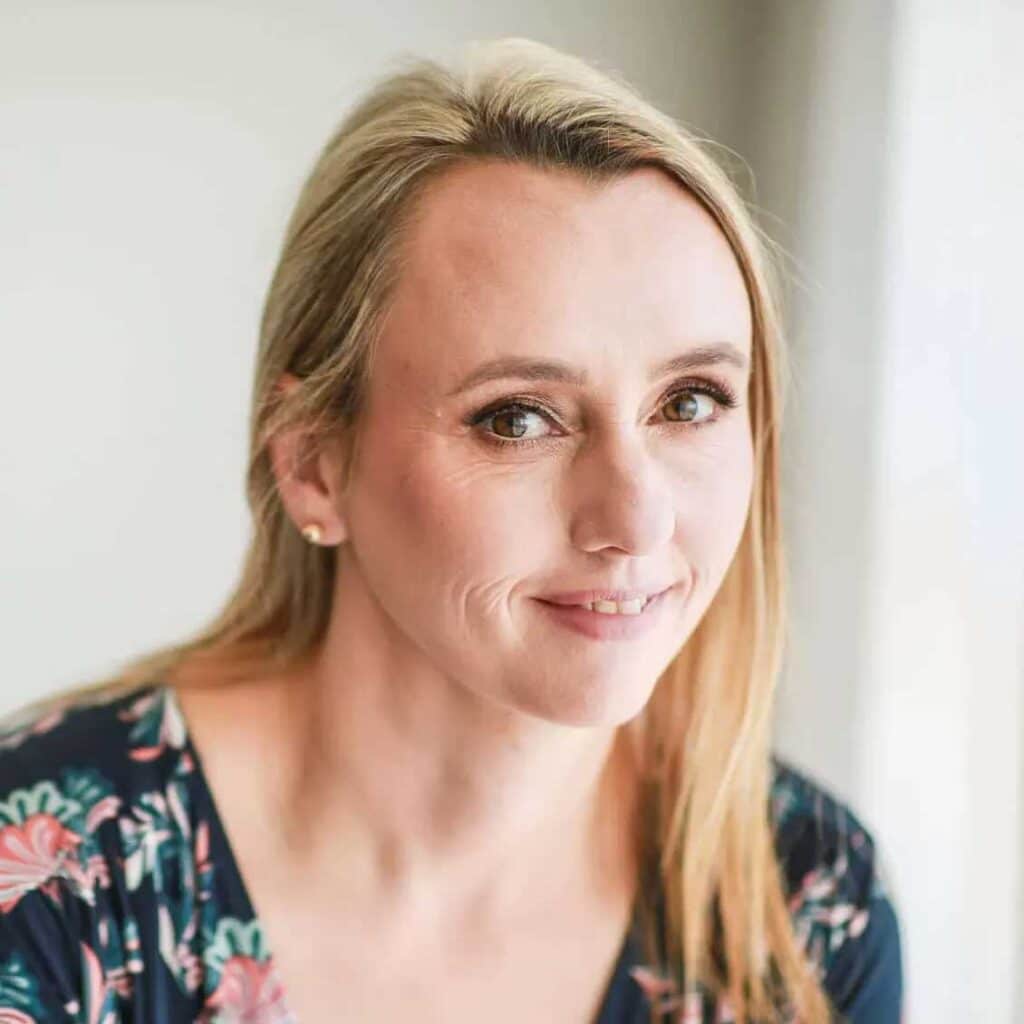 A Woman In A Floral Top Smiles Beautifully In Front Of A Window In Sydney.