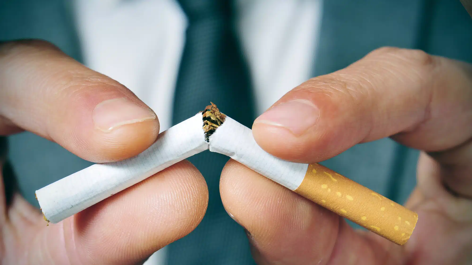 A Close-Up Of Hands Breaking A Cigarette In Half, Symbolizing Quitting Smoking.